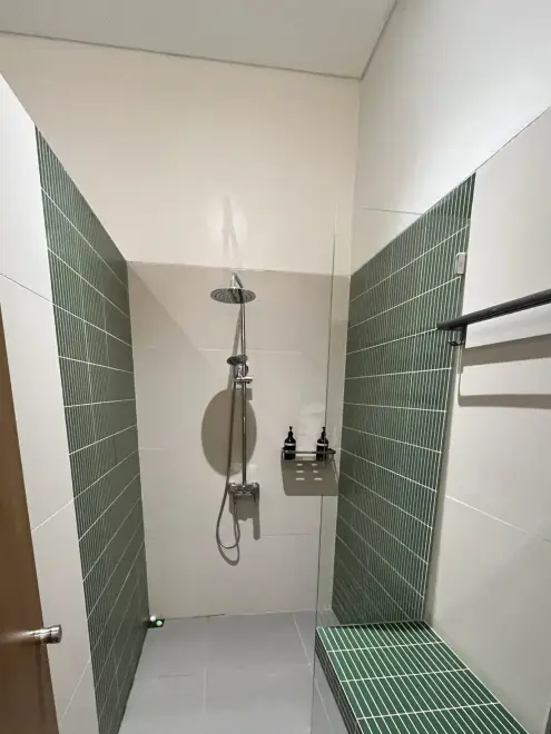 Shower with green tiles and a bench