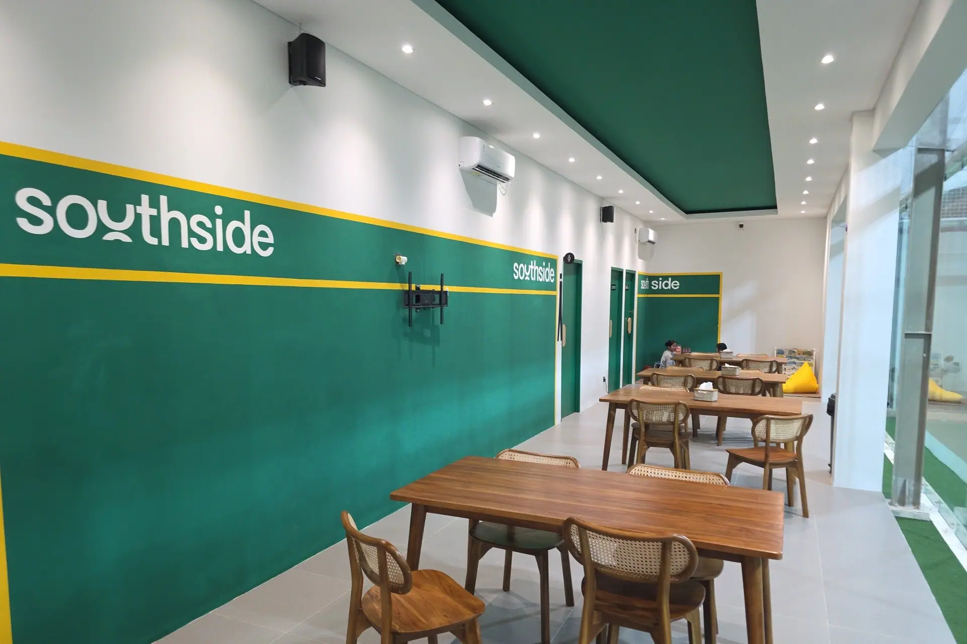 Café tables beside the green Southside feature wall